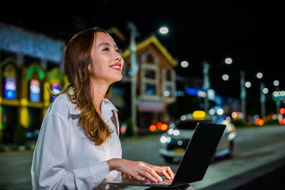 Young woman using mobile phone at night