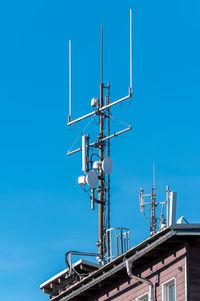 Low angle view of communications tower against clear blue sky