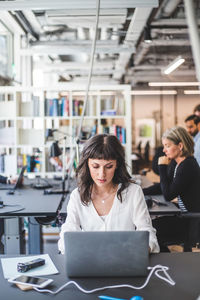 Woman using phone while sitting on table