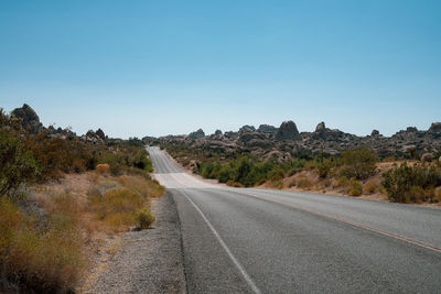 Road amidst trees against clear sky