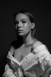 Portrait of young woman against black background