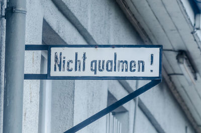 Low angle view of information sign hanging on building