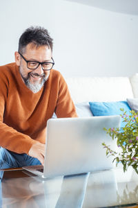 Businesswoman using laptop while sitting on sofa at home