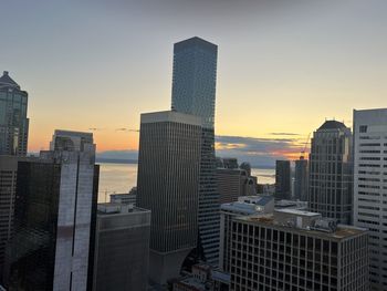 Modern buildings in city against sky during sunset