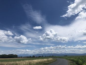 Road amidst field against sky