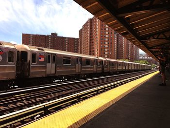 Train at railroad station in city against sky