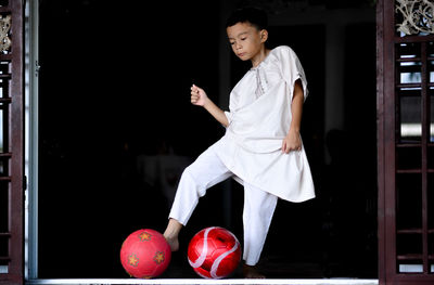 Low angle view of boy kicking red balls