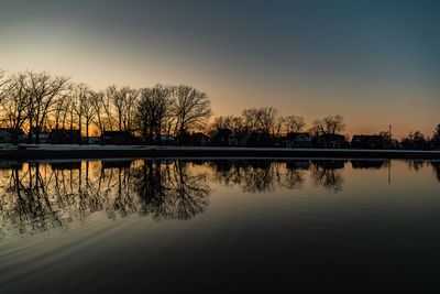 Reflection of trees in lake at sunset