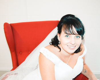 Portrait of smiling bride sitting on chair