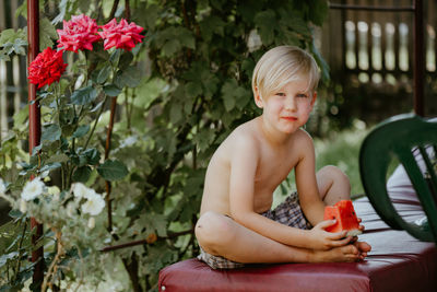 Portrait of shirtless boy sitting outdoors