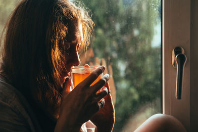 Woman enjoying tea by rainy window