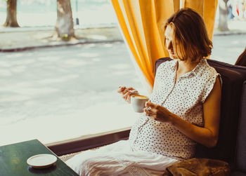 Woman holding coffee while sitting on table