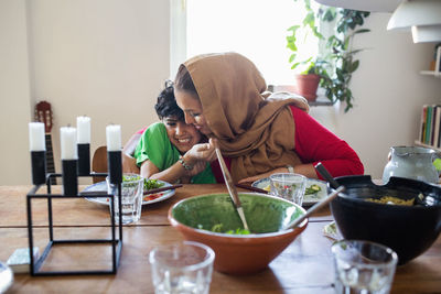 Happy mother and son embracing at dining table