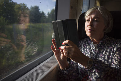 Senior woman taking picture through train window