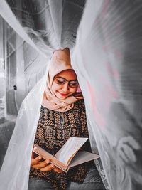 Portrait of young woman reading book