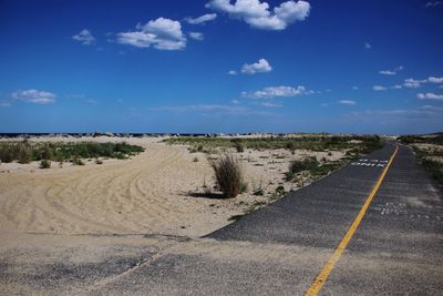 Road passing through land against sky