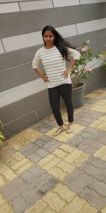 Portrait of a smiling young woman standing on footpath