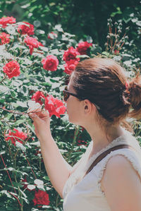 Side view of young woman holding red roses