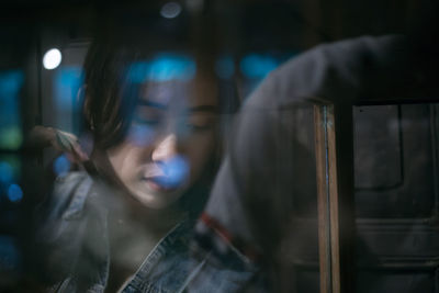 Close-up of woman looking away seen through window