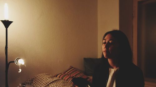 Young woman sitting on bed at home