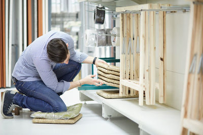 Side view of man arranging objects in store