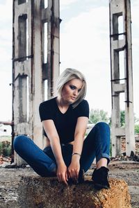 Young woman sitting in front of wall