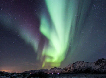 Aurora polaris over mountains against sky