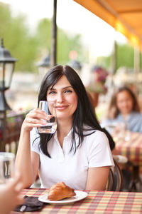 Portrait of a smiling young woman sitting at restaurant table