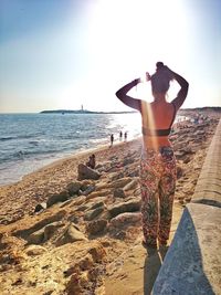 Rear view of woman standing on beach against clear sky