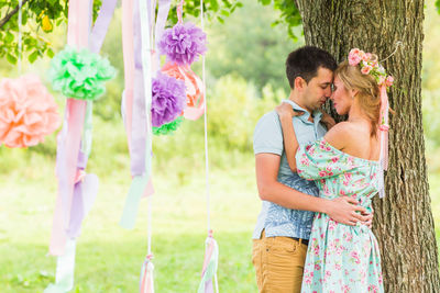 Young couple holding pink flowering plants