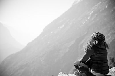 Rear view of woman standing on mountain against clear sky