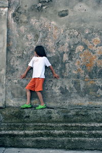 Boy walking on weathered wall