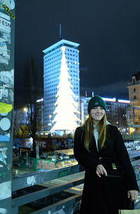 Portrait of young woman standing against buildings