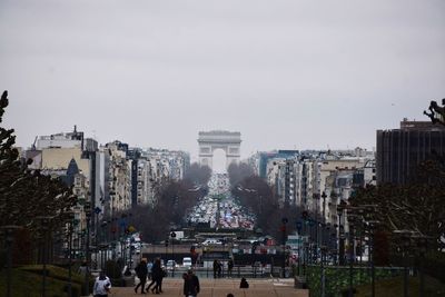 Distant view of arc de triomphe amidst buildings against sky in city