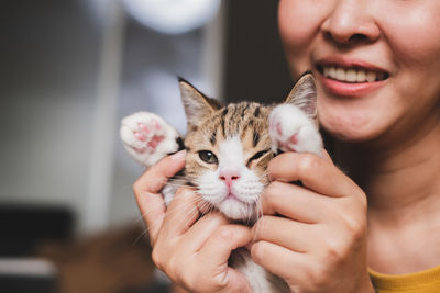 Midsection of smiling woman holding kitten