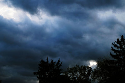 Low angle view of silhouette trees against cloudy sky