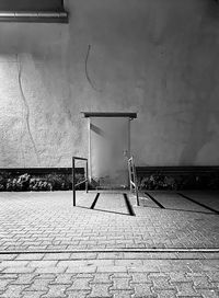 Empty chair on footpath against wall