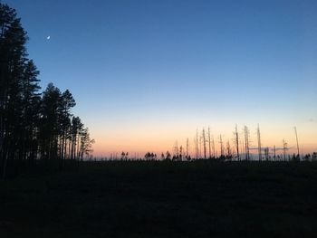 Silhouette trees on landscape against clear sky during sunset
