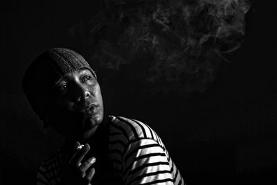 Mature man smoking cigarette against black background