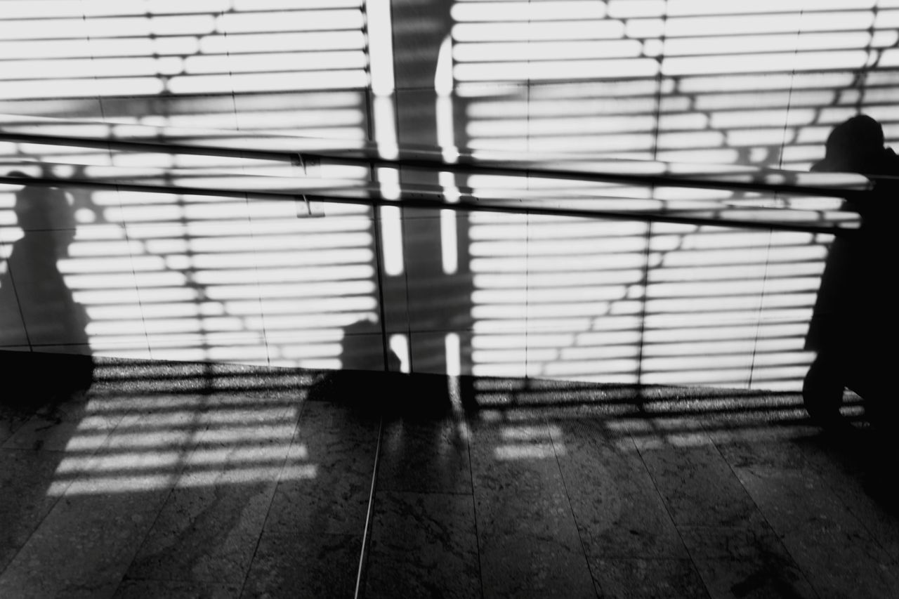 SHADOW OF MAN WALKING ON RAILING