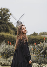 Portrait of smiling young woman standing against sky