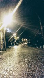 Illuminated street light against sky at night