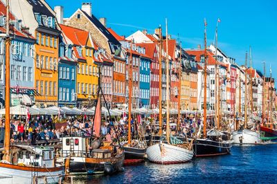 Sailboats moored on sea by buildings in city