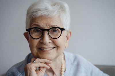 Happy senior woman with hand on chin at home