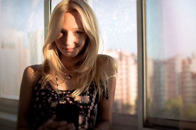 Portrait of young woman against window