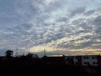 Silhouette trees and buildings against sky at sunset