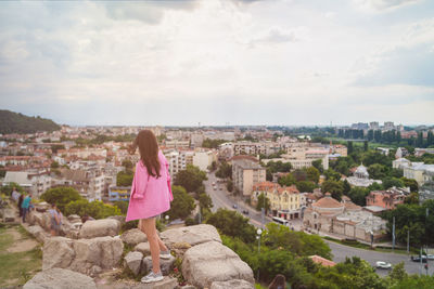 Rear view of woman looking at city buildings against sky