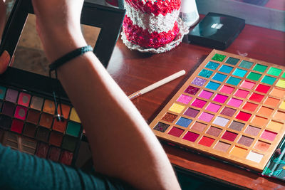 Woman in front of her dressing table holding her worn out eyeshadow palette. 