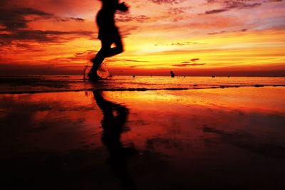 Silhouette woman by sea against sky during sunset