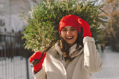 A beautiful girl in a red hat carries a christmas tree. christmas tree